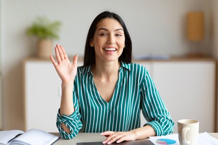 Hello, New Job. Cheerful Businesswoman At Laptop Waving Hi Sitting At Workplace In Office.の写真素材
