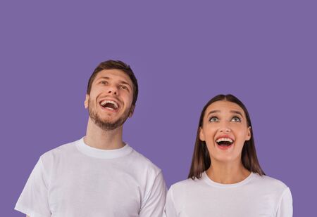 Wow. Closeup headshot of thrilled couple looking up at copy space isolated on pastel purple studio wallの写真素材