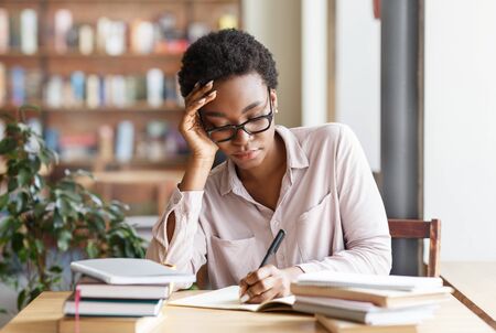 Industrious young woman with books studying at urban cafe