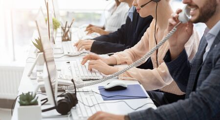 Closeup view of customer support operators working at call centre, copy space. Panorama