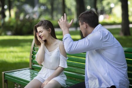 Domestic violence concept. Angry husband trying to beat his crying wife at parkの写真素材