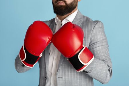 Business competition concept. Unrecognizable entrepreneur in boxing gloves on blue background, closeupの写真素材
