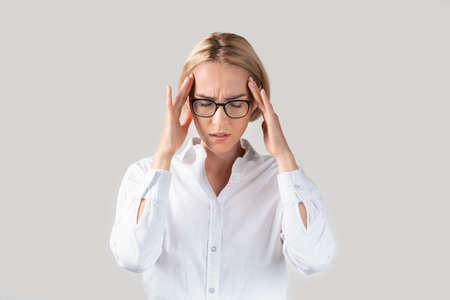 Tired office employee having terrible headache or suffering from work stress on light studio...