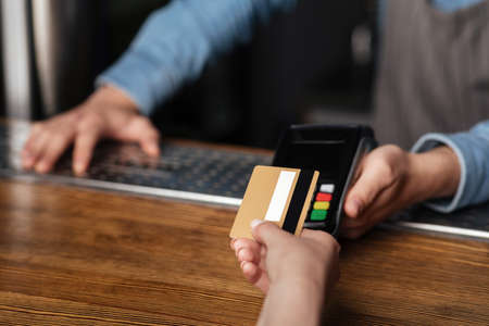 Fast payment for drinks. Girl uses credit card, barman holds terminal on bar counter, cropped, free...