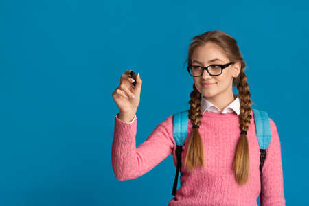 Teen girl in glasses writes marker on screen, empty space
