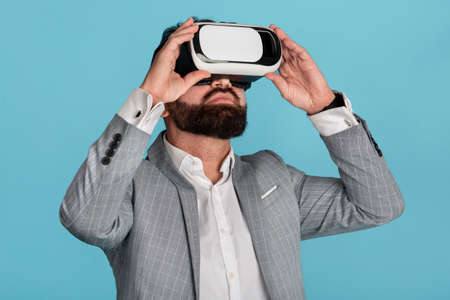 Businessman in virtual reality headset exploring cyberspace against blue backgroundの写真素材