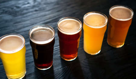 Different types of beers. Ale, dark, light and unfiltered beer and lager, in glasses on dark wooden counter, top view, close upの写真素材