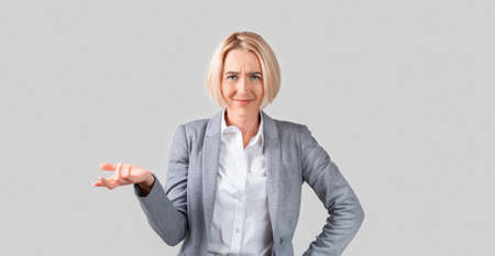 Puzzled mature lady boss asking for explanation on light background, panoramaの写真素材