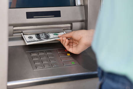 Unrecognizable woman getting dollar cash money from ATM outdoors, cropped image with celective focusの写真素材