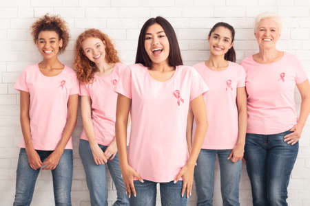 Happy Korean Girl In Breast Cancer T-Shirt With Ribbon Standing With Support Group Smiling To Camera On White Background.の写真素材