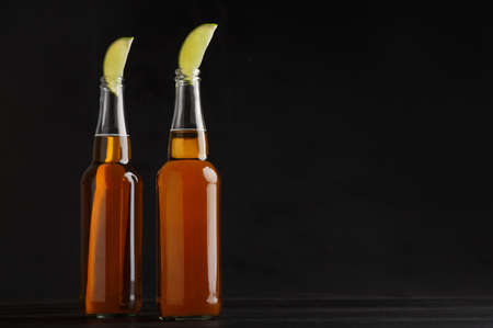 Beer order. Two bottles with lager and slices of lime isolated on black background, free spaceの写真素材