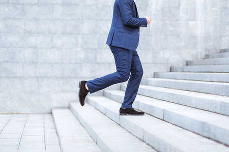 Cropped view of entrepreneur running up stairs, being late for work in busy cityの写真素材