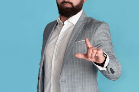 Cropped view of young entrepreneur touching imaginary screen over blue background, empty spaceの写真素材