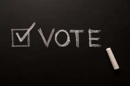 Tick near text vote symbolize US elections in 3 November 2020, chalk on blackboardの写真素材
