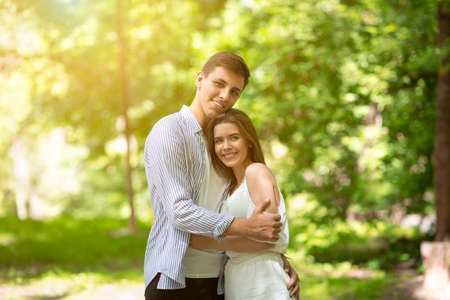 Romantic times together. Young couple in love embracing at sunny summer parkの写真素材