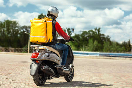 Food Delivery Service. Courier With Yellow Backpack Riding Scooter Delivering Restaurants Meals In...