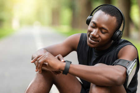 Closeup of happy african sportsman looking at his fitness watch, copy space