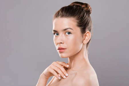 Naked attractive young woman looking at camera, grey studio backgroundの写真素材