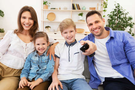 Cheerful Family Watching TV Switching Channels Sitting On Couch At Home. Relaxing Together On...