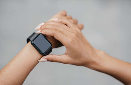 Check activity of body. African american girl check smart watch with blank screen on gray background, pov, close up, free spaceの写真素材