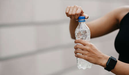 African american young woman with smart watch opens water bottle, outdoors, cropped, free space