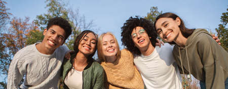 Portrait of overjoyed multiracial teenagers having fun outdoors, posing at camera, panorama