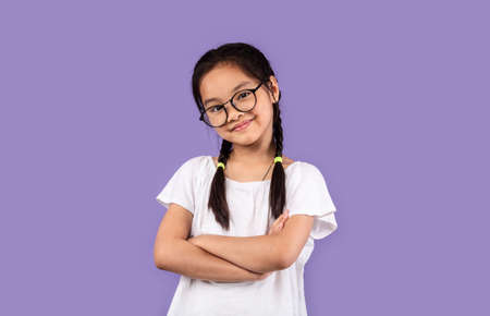 Little Chinese Girl Wearing Eyeglasses Posing Crossing Hands Standing Over Pastel Purple Background,...