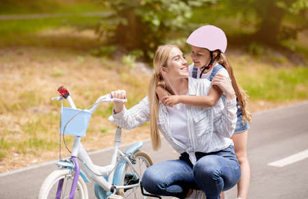 Mom Teaching Her Little Daughter To Ride Bicycle Outdoors In Park. Family Adveture Concept