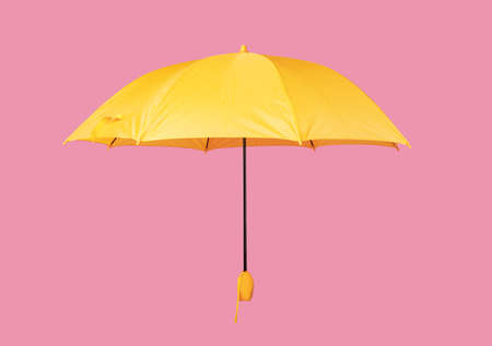Opened yellow umbrella isolated on pastel pink studio background