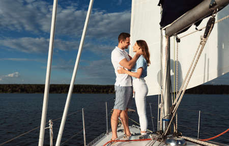 Romantic Date On Yacht. Loving Couple Embracing Standing On Sailboat Deck Enjoying Honeymoon Sailing On River Outdoor. Copy Spaceの写真素材