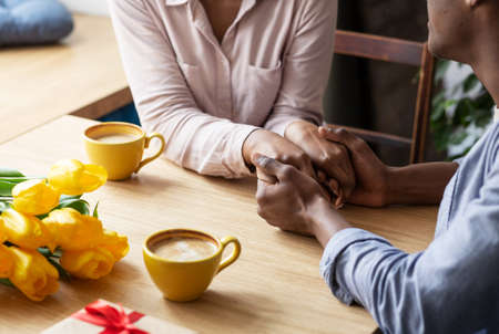 Closeup view of millennial black couple holding hands at coffee shopの写真素材