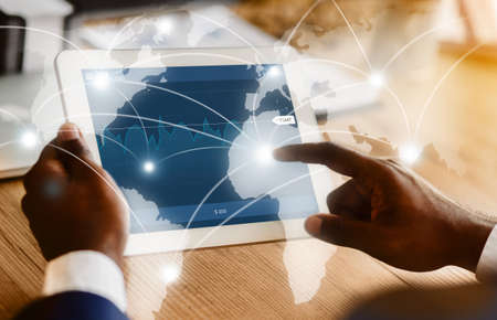 Cropped image of african businessman touching digital tablet screen with business worldwide map...