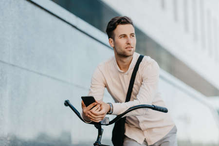 Modern young man, environmentally friendly transport and road to work. Attractive serious...