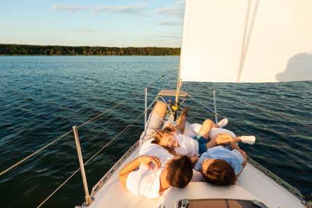 Sea Sailing. Family Lying On Yacht Deck Relaxing On Sailboat Ride On Summer Day. Free Space For Text