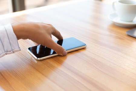 Notification. Closeup of lady taking cell phone off desktop or laying it down on tableの写真素材