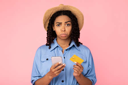 Mobile Banking Problem. Upset Black Girl Holding Phone And Credit Card Standing On Pink Studio...