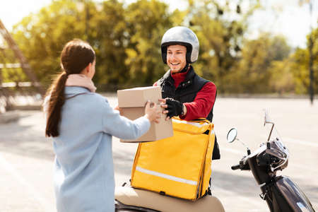 Food Delivery. Courier Guy Delivering Parcel Boxes With Restaurant Order To Customer Outdoorsの写真素材