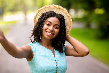 Smiling black lady taking selfie or chatting online at summer parkの写真素材