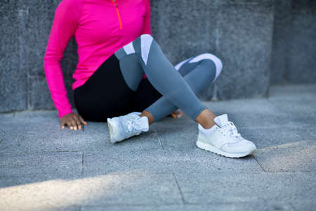 Cropped of sporty african woman resting on stone construction, training outdoorsの写真素材