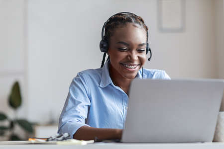 Hotline Support Service. Smiling african woman call center operator in headset working in modern...