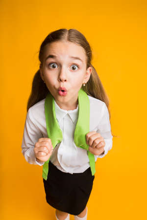 Surprised Elementary Student Girl Looking At Camera In Amazement Posing On Yellow Background In...