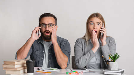 Terrible news at work. Frightened and shocked man with beard and glasses and with open mouths in workplace in office, panorama, copy spaceの写真素材