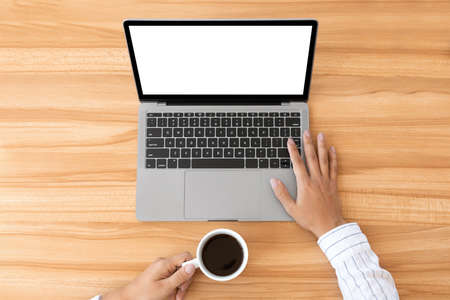 Top view of unrecognizable lady using laptop with white black screen and holding cup of coffee