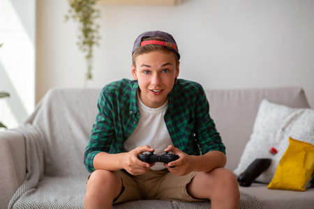 Excited teenager playing video games at home, eating unhealthy food, enjoying his free timeの写真素材