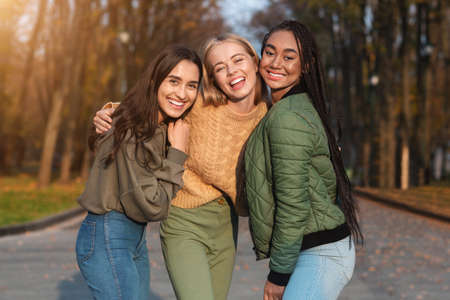 Three pretty multiethnic teen girls posing in public park