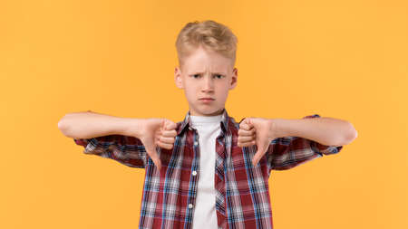 Disagreement, Disgust and Negative Expressions. Closeup portrait of serious pupil showing two thumbs...