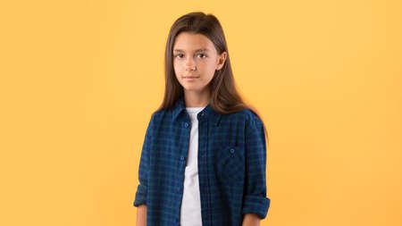 Portrait of beautiful casual caucasian schoolgirl posing and looking at camera isolated over pastel orange studio wallの写真素材