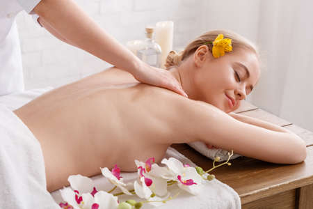 Anti-aging procedures. Professional doing massage of girl on table with orchidsの写真素材