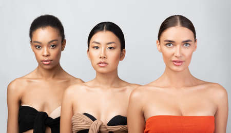 Female Beauty Concept. Three Multicultural Model Girls Posing Wearing Underwear Looking At Camera Over Gray Studio Background.の写真素材