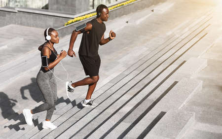 Cardio Training. Smiling African Couple Jogging On Steps In Urban Park, Enjoying Healthy Lifestyle,...